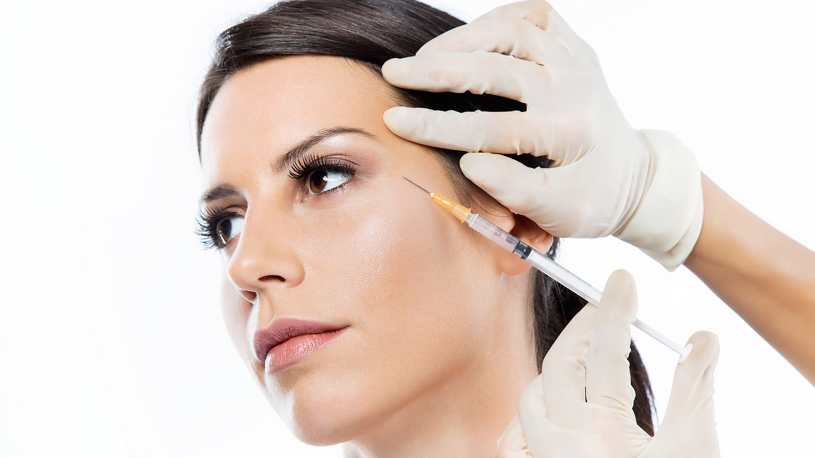 Portrait of beautiful young woman getting botox cosmetic injection in her face over white background.